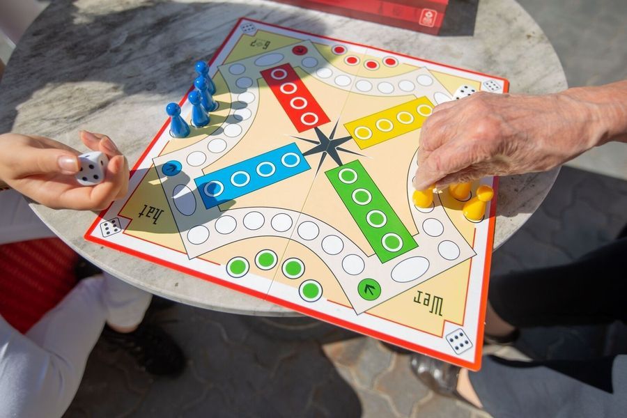 Senior spielt mit einem Kind Mensch ärgere dich nicht