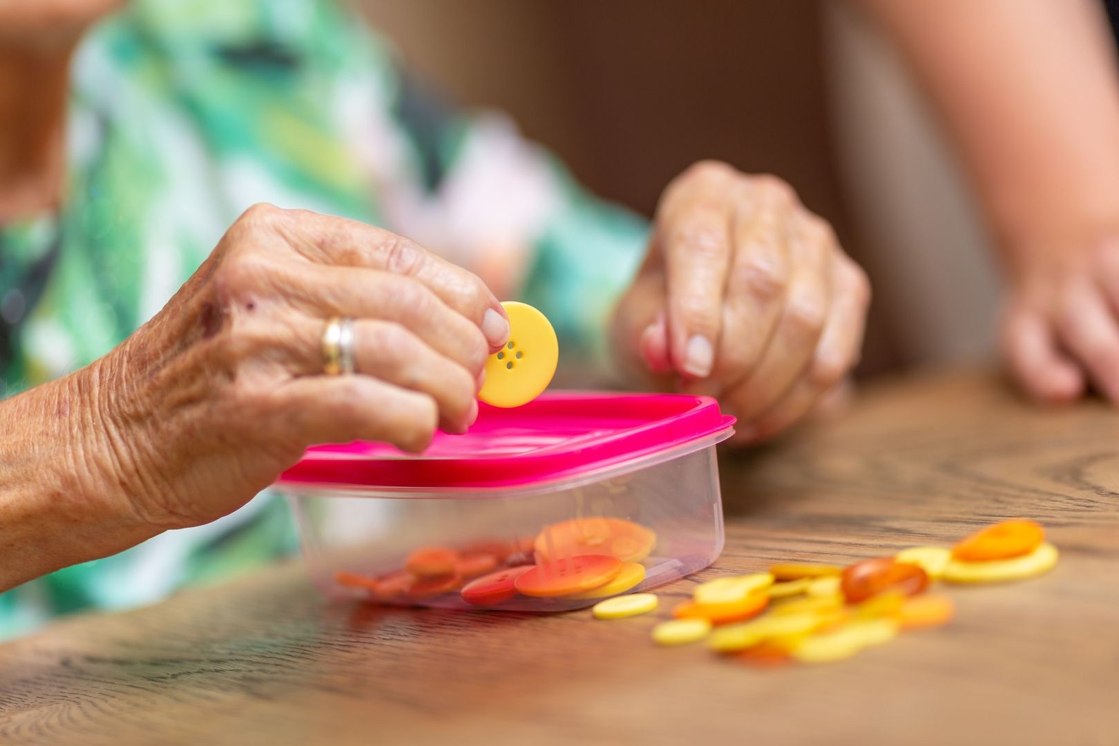 Seniorin übt eine motorische Übung mit Knöpfen