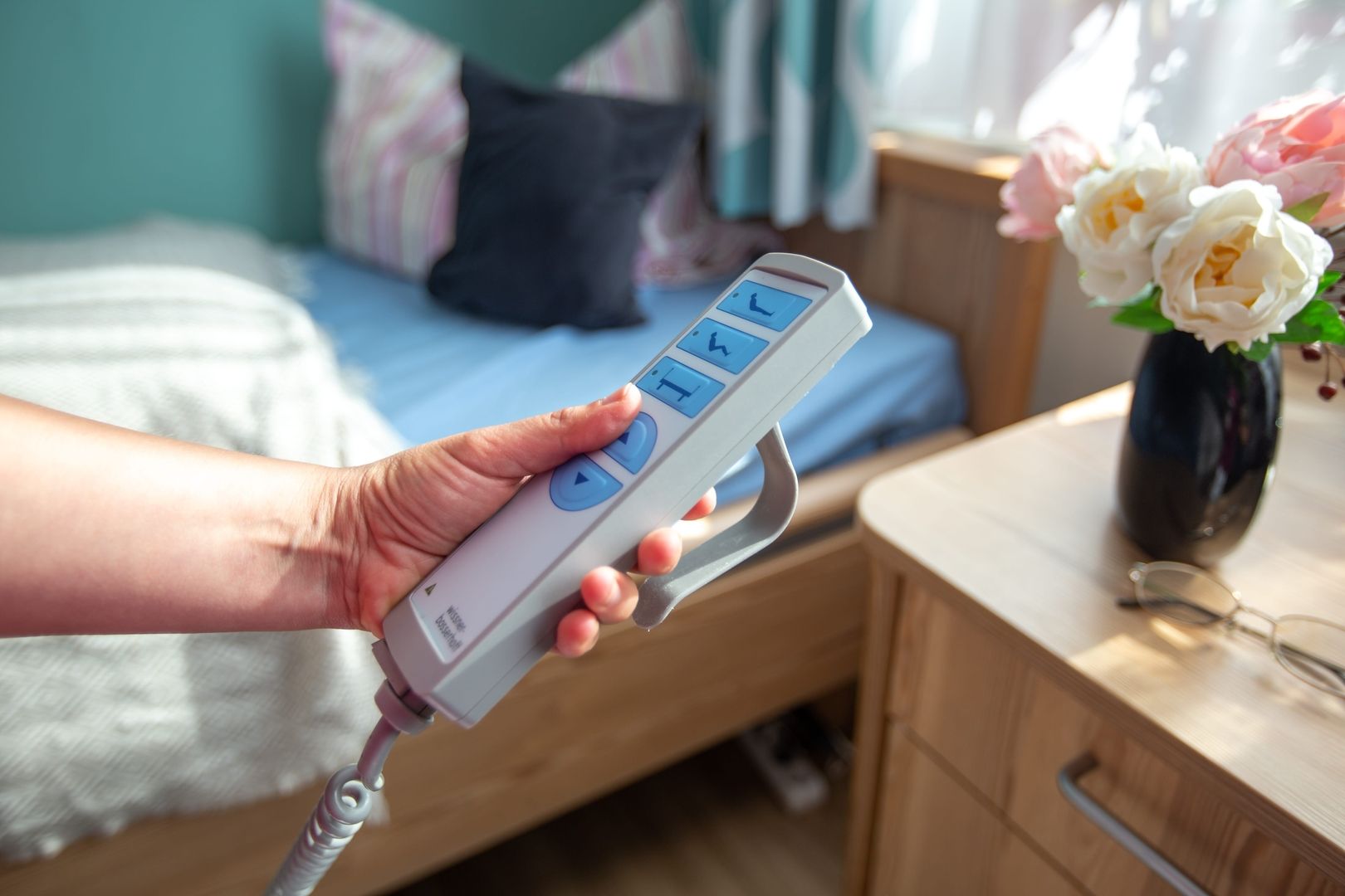 Eine Hand bedient eine Fernbedienung für die Pflegeeinrichtung