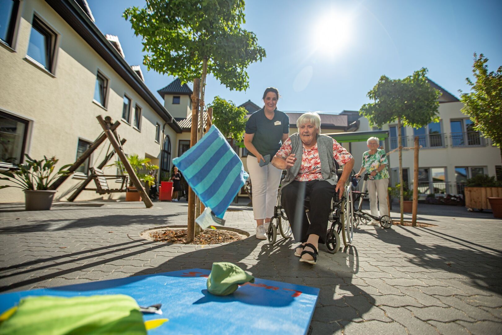 Pflegerin und Seniorin werfen im Freien Kissen